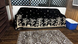 Ein Zimmer mit einem gemusterten Teppich, einem Sofa mit Nachtstern-Motiv und einer blauen Aufbewahrungsbox.