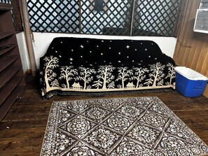 A room with a patterned rug, a sofa with a starry night design, and a blue storage bin.