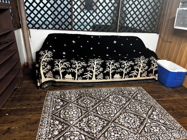 Ein Zimmer mit einem gemusterten Teppich, einem Sofa mit Nachtstern-Motiv und einer blauen Aufbewahrungsbox.