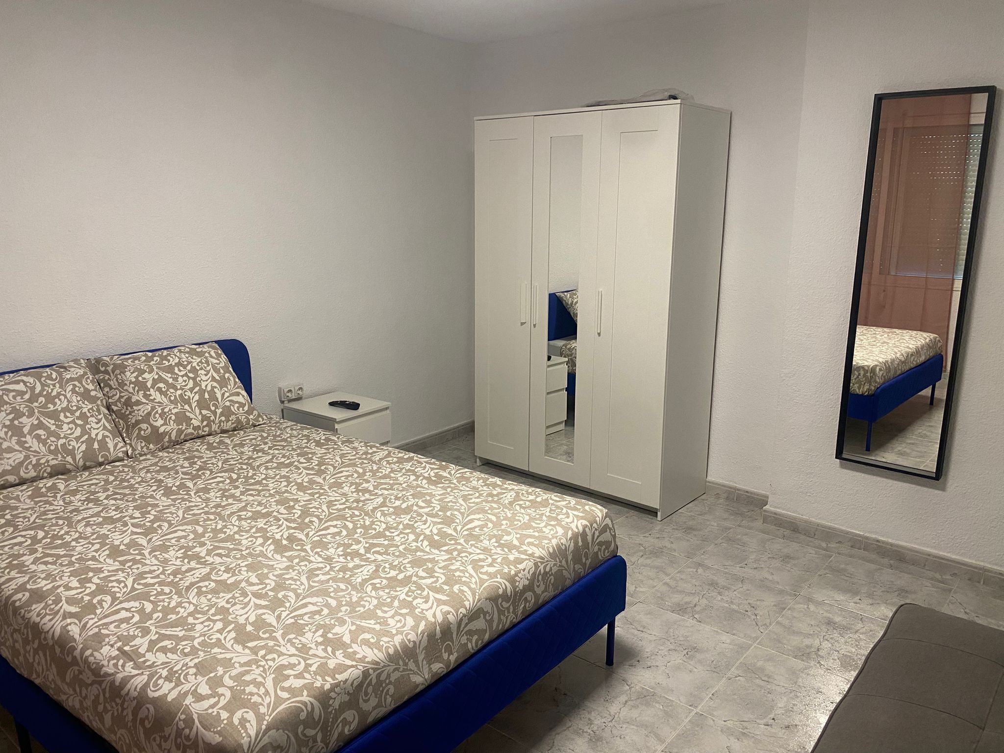 Une chambre à coucher comprenant un lit, une armoire, une table de chevet et un miroir.