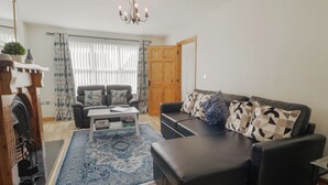 A living room with a black leather sofa, a coffee table, and a patterned rug. - The Sperrin Getaway (Omagh)