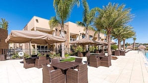 An outdoor patio area with wicker furniture and umbrellas, a pool, and palm trees. - Modern Magic Village Home for 12 With Grill 3131 (Kissimmee)