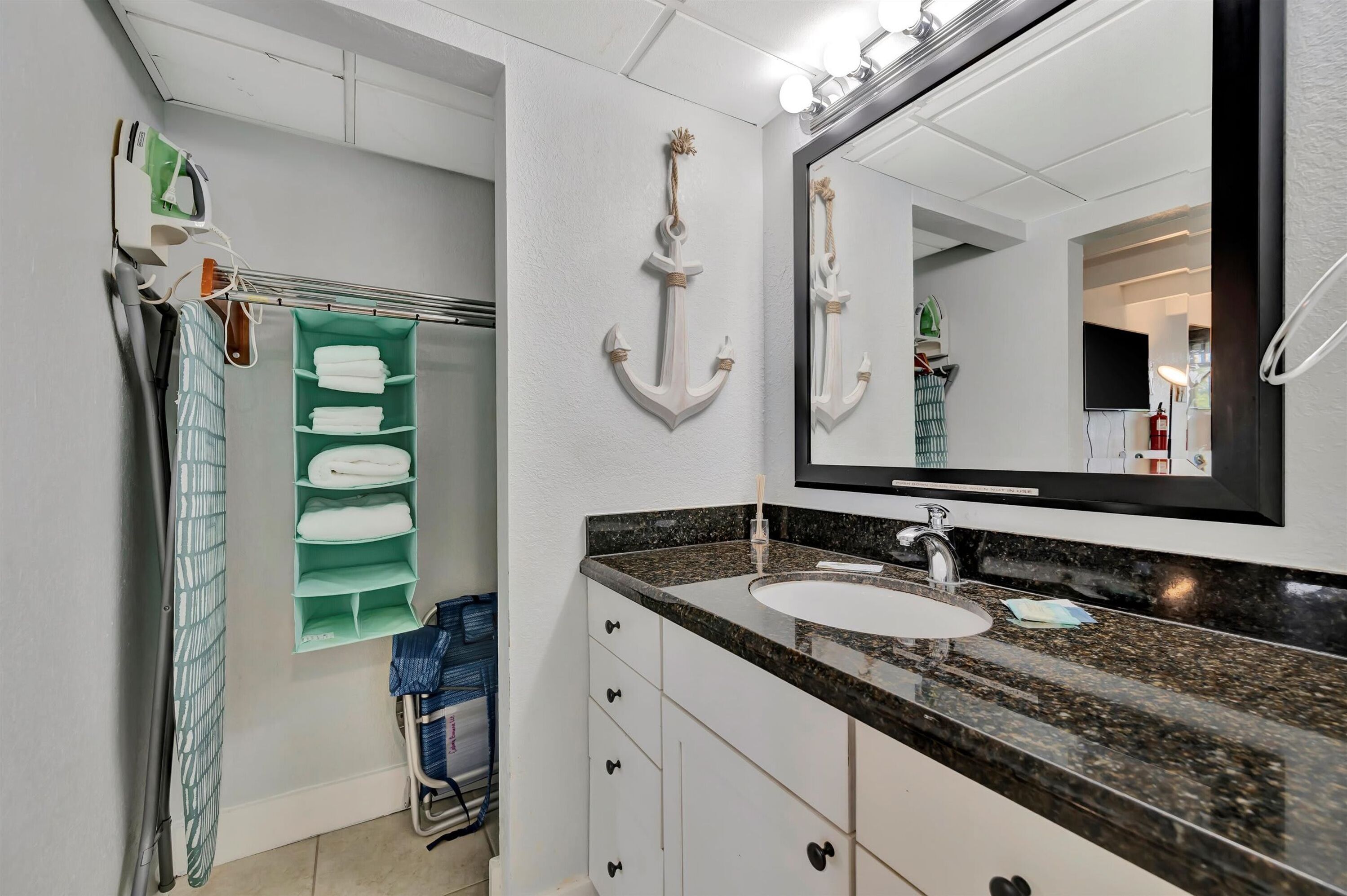 A bathroom with a sink, mirror, and towel rack.