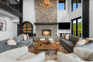 A modern living room with a stone fireplace, grey sofas, and a coffee table.