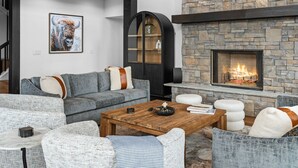 A modern living room with a stone fireplace, grey sofas, and a coffee table.