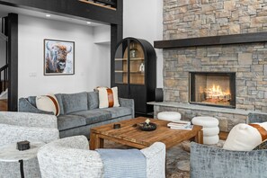 Una sala de estar moderna con chimenea de piedra, sofás grises y una mesa de centro.