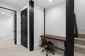 Ein Eckzimmer mit Schreibtisch, Stuhl und einer Tür.