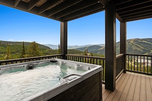 A hot tub on a wooden deck with a mountain view. - Lavish 6 Bedroom Ski Accessible Home (Big Sky)