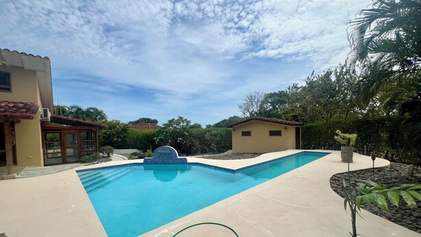 Una piscina rectangular con borde de azulejos azules, rodeada por una plataforma de concreto.