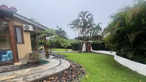 Un jardín bien cuidado con un sendero de piedra, césped y una variedad de plantas, incluyendo palmeras.