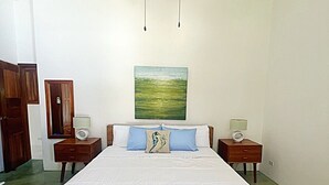 Een slaapkamer met een houten bed, twee nachtkastjes met lampen, een plafondventilator en een schilderij aan de muur.