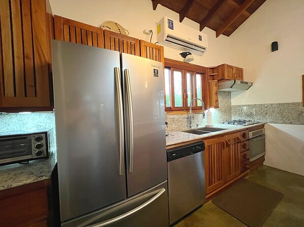 A kitchen with stainless steel appliances, wooden cabinets, a built-in dishwasher, and a window above the sink.