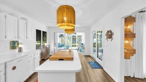 A modern kitchen with white cabinetry, a wooden island, and a large pendant light.