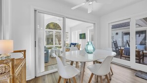 A dining area with a white table, four white chairs, and a teal vase.