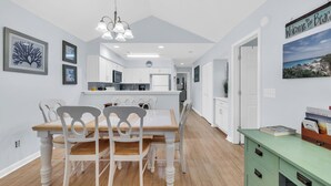 Une cuisine moderne avec des meubles blancs, une table à manger en bois et un buffet vert.