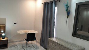 Pieni, moderni huone, jossa on pyöreä pöytä, tuoli, puinen lipasto ja peili seinällä.