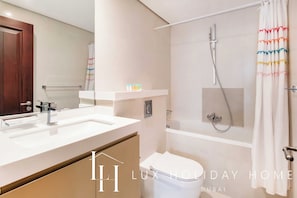 A modern bathroom with a double sink, a bathtub, and a shower.
