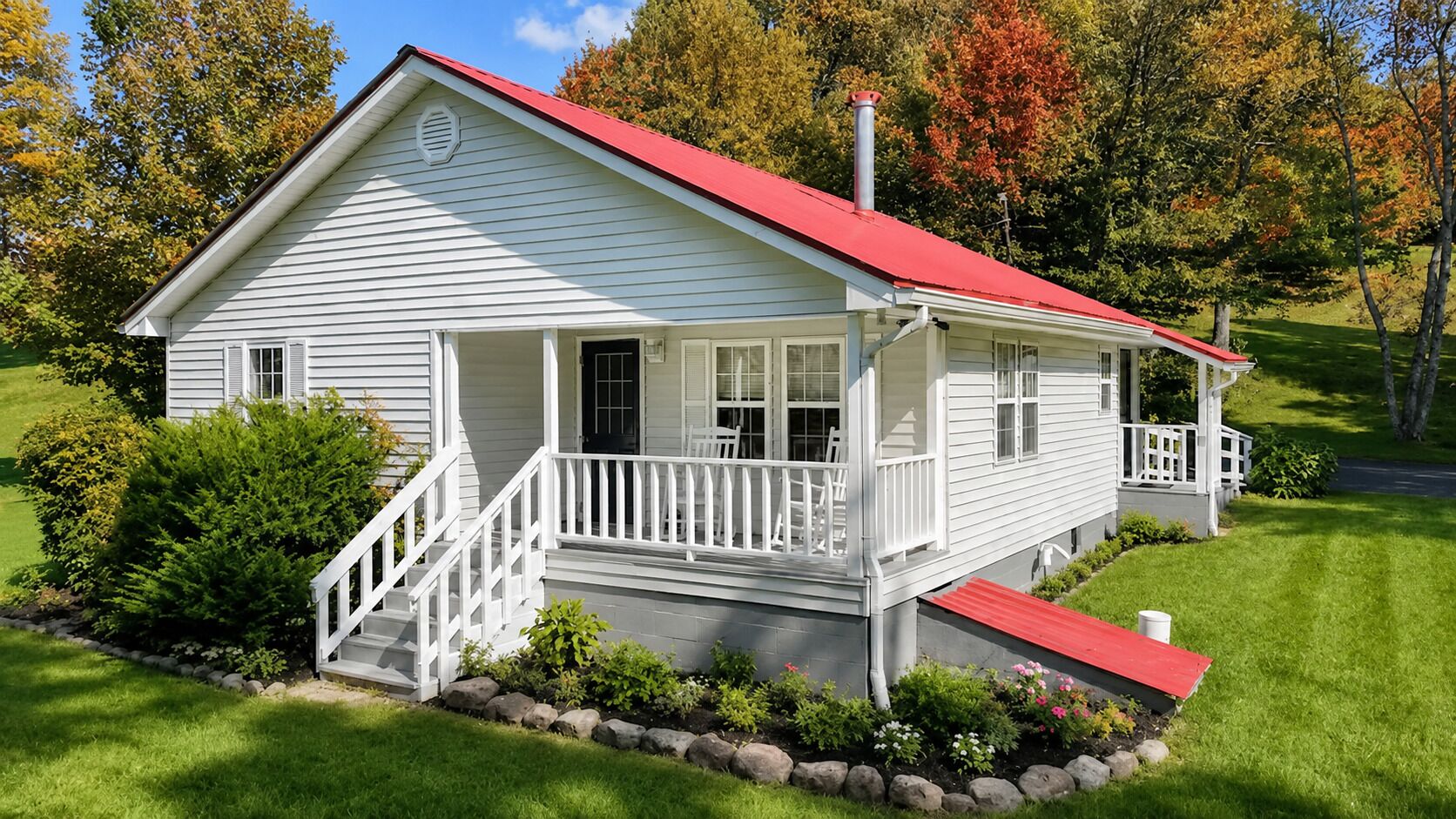 A single-story house with a red roof, white siding, and a front porch with white railings.