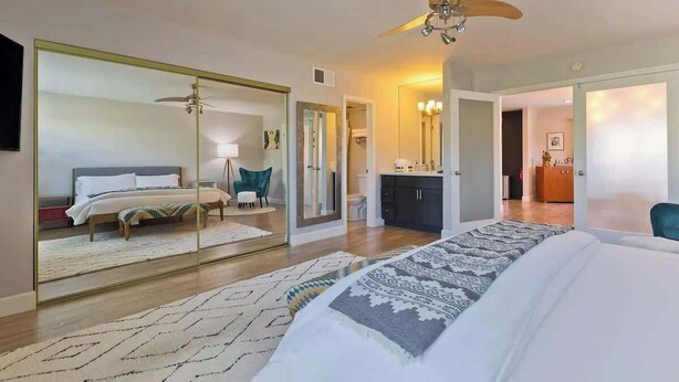 A modern hotel room with a large bed, a mirror, a ceiling fan, and a walk-in closet. - Palm Springs Oasis w/ Pool & Spa (Palm Springs)