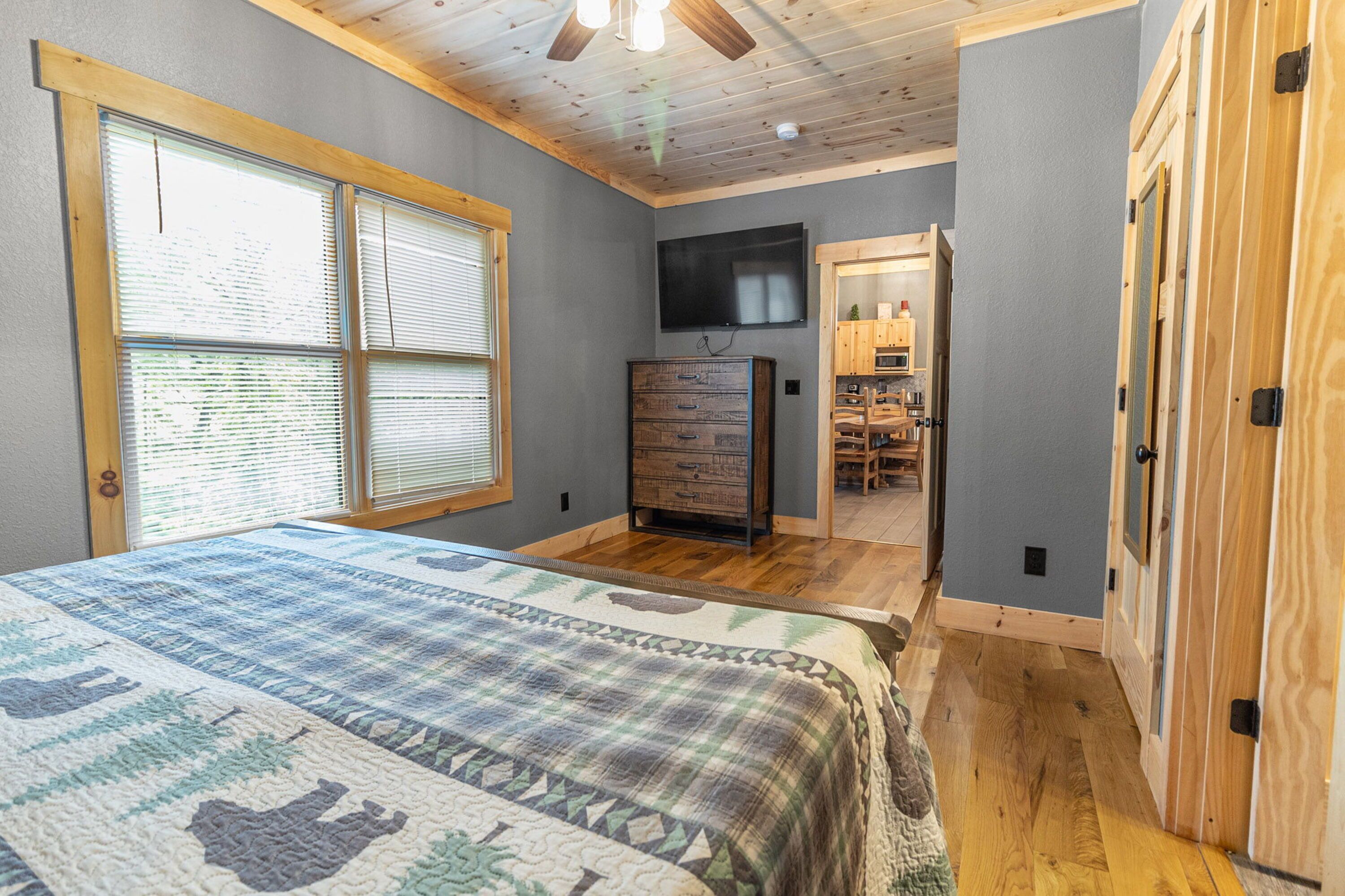 Une chambre avec un grand lit, un plafond en bois et un téléviseur fixé au mur.