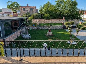 Une cour avec un mur en pierre, un petit jardin et un espace aménagé avec une chaise et une table.