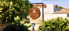 A sign with the name 'Mlinova' and a windmill icon, indicating a location or establishment. - Mlinova Küçükköy (Ayvalık)