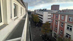A high-rise building with a view of a pedestrian area below, featuring a mix of modern and traditional architecture. - Hotel Horstmann (Münster)