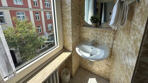 A bathroom with a window, a sink, a mirror, and a towel rack. - Hotel Horstmann (Münster)