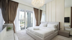A modern bedroom with a large bed, a TV, and a balcony with a city view. - KeyRock - Palm View Apt with Pool (Dubai)