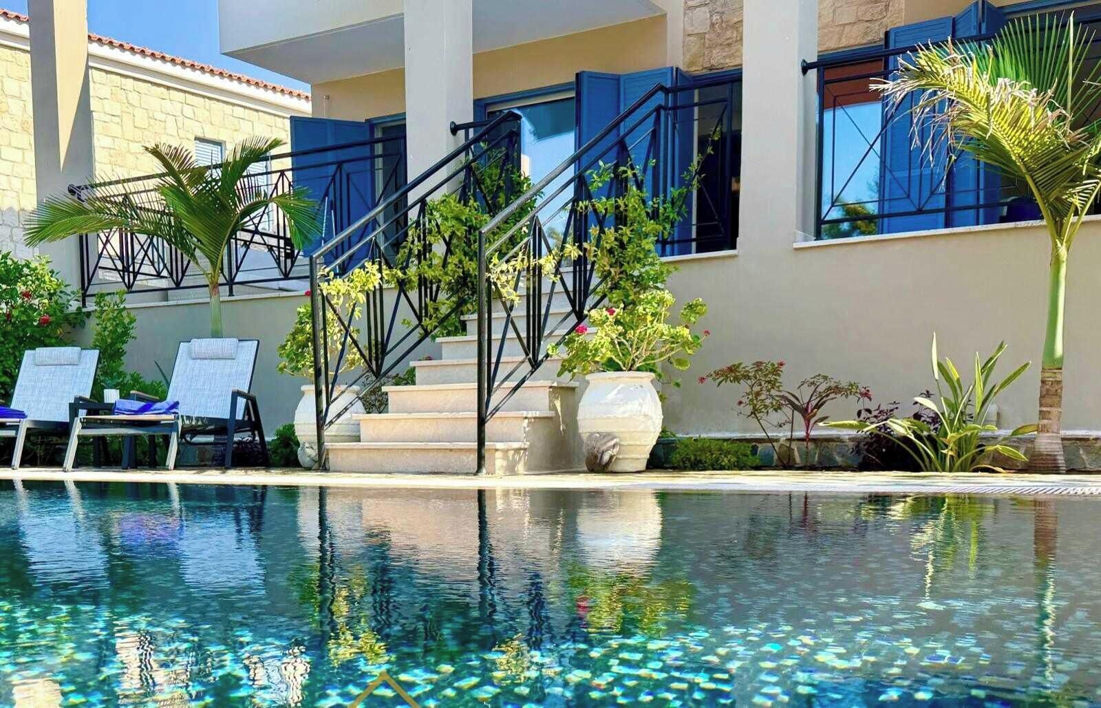 Una piscina con agua cristalina, rodeada de tumbonas y plantas en macetas.
