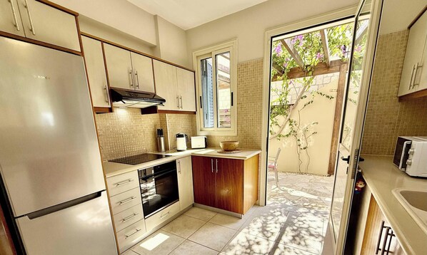 A compact kitchen with a refrigerator, oven, and a window overlooking a garden.