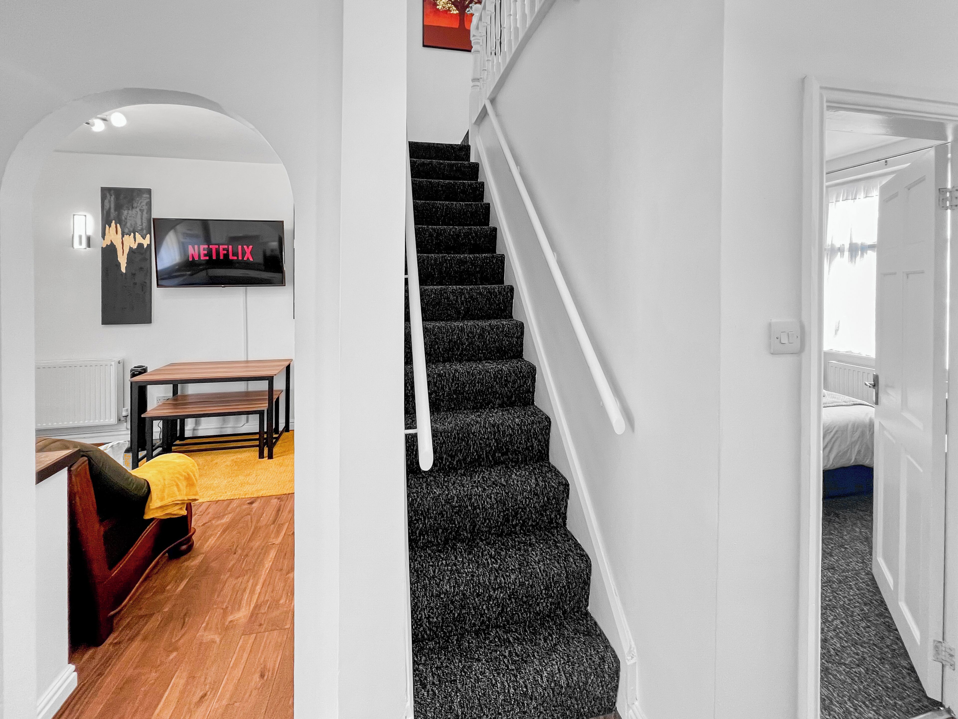 A staircase with black carpeted steps leading to a bedroom.