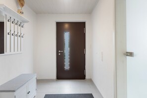 Ein Flur mit einer dunklen Tür, weißen Wänden, einem weißen Schrank und einem kleinen Teppich.