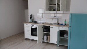 A kitchen with white cabinets, a sink, a microwave, and a teal refrigerator.