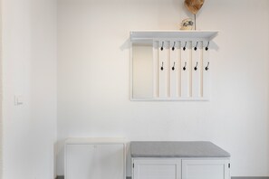 A white room with a cabinet, a shelf with hooks, and a small decorative item. - Apartment 'Spielmann' (Sauldorf)