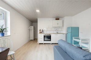 Un espace de vie compact comprenant un coin cuisine, un coin repas avec une table et des chaises, et un canapé.