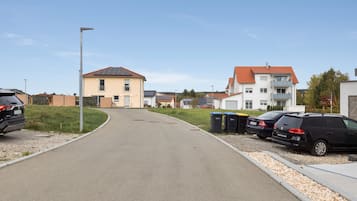 Eine Wohnstraße mit Häusern, parkenden Autos und blauem Himmel.