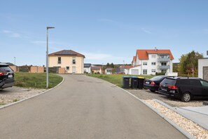Eine Wohnstraße mit Häusern, parkenden Autos und blauem Himmel.