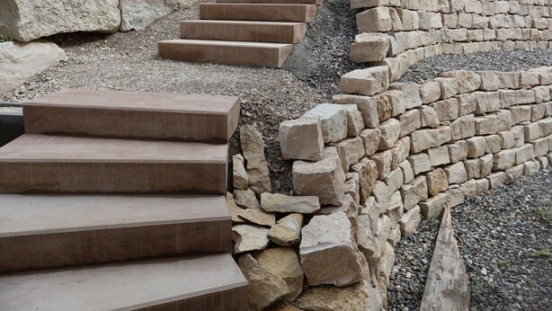 A set of stone steps leading up to a stone wall.