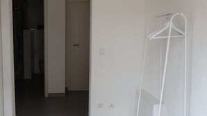 A hallway with a white metal drying rack, a door, and a tiled floor.