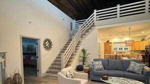 Ein geräumiger Wohnbereich mit Treppe zu einer oberen Ebene, einem Essbereich und einer Küche.