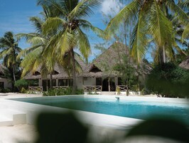 Un resort con bungalows de techo de paja, una piscina y palmeras.