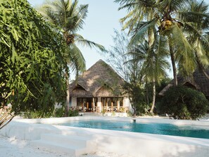 A resort with a pool, thatched-roof structures, and palm trees. - Bahati Sunset Bungalows (Michamvi)