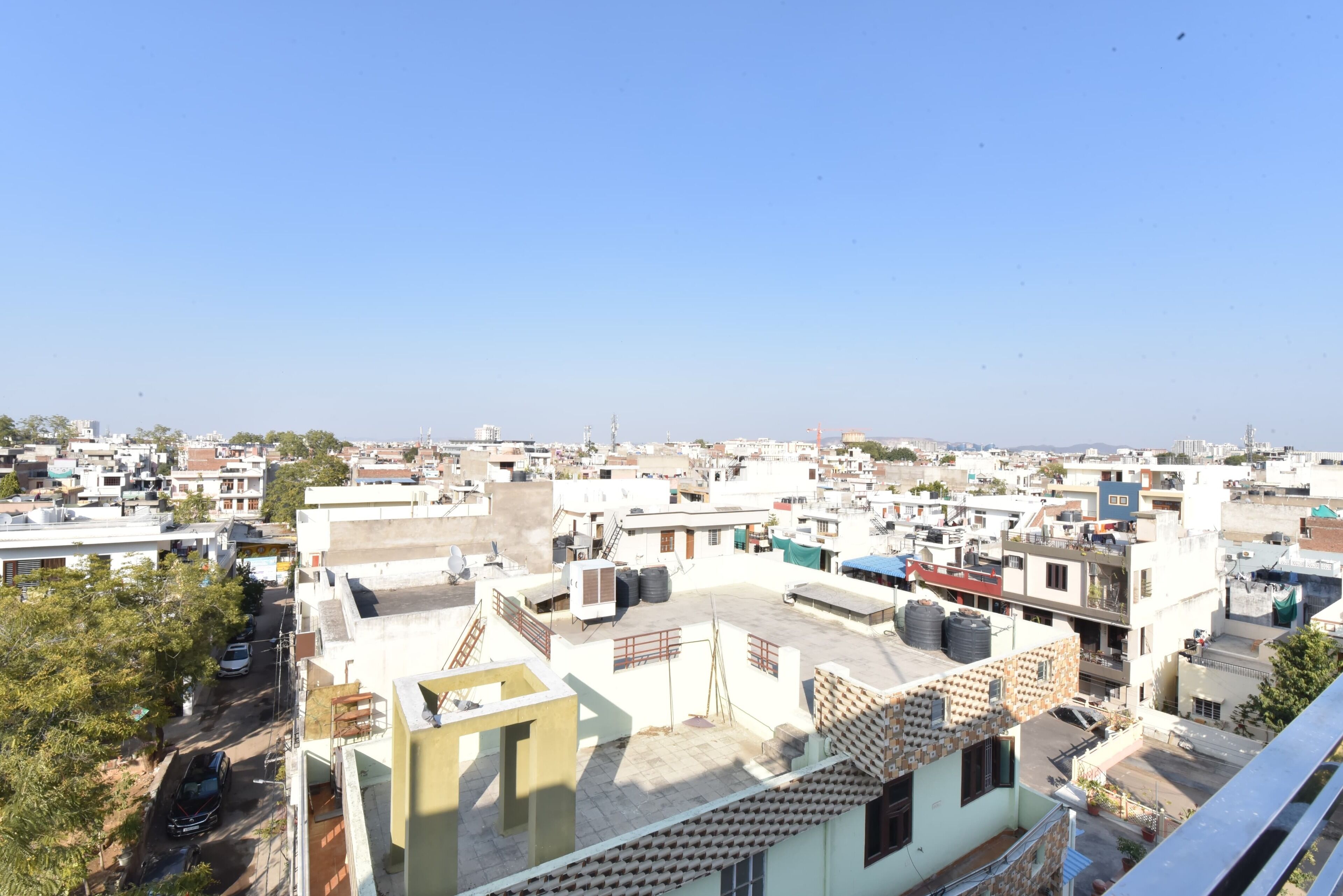 Zona residencial con varios edificios, algunos con techos planos y otros con techos inclinados. Se observan depósitos de agua en algunas cubiertas, y unos pocos árboles dispersos por la zona.
