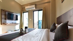 Een hotelkamer met een groot bed, een flatscreen televisie aan de wand bevestigd, een airconditioning en uitzicht op de stad.