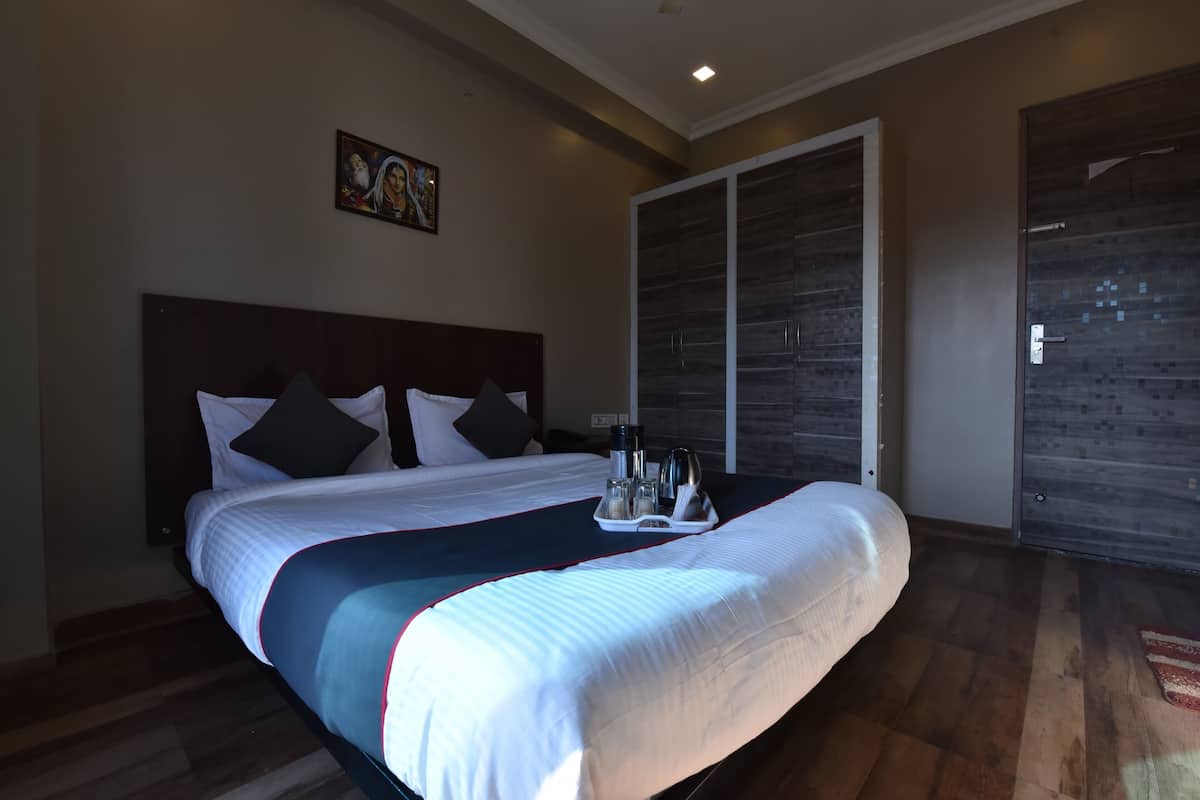 Una cama bien hecha con un bandeja de artículos de aseo, un armario amplio y un cuadro en la pared.