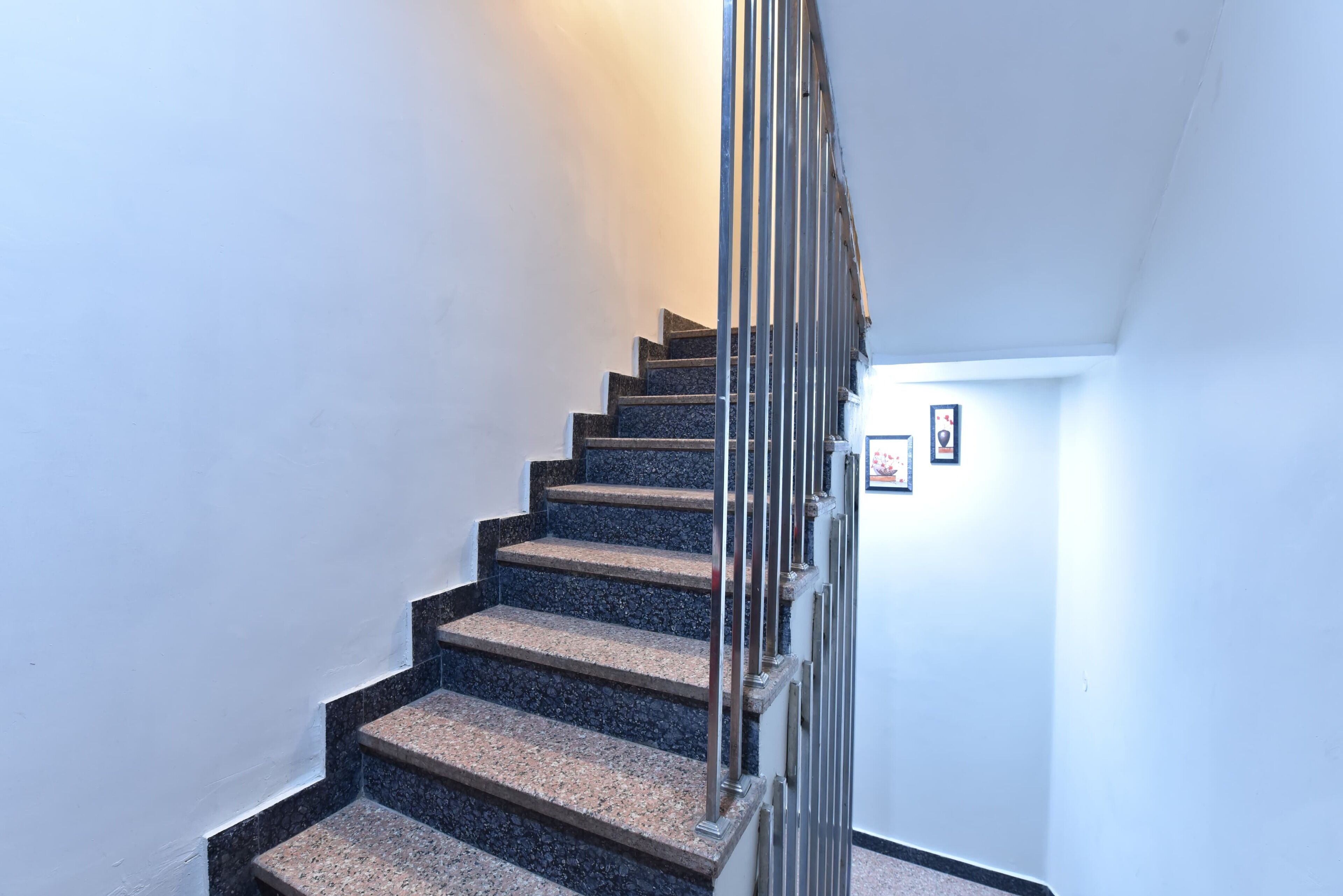 A staircase with a metal railing, carpeted steps, and a white wall.