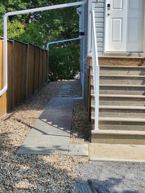 A pathway leading to a wooden door with a metal handrail.