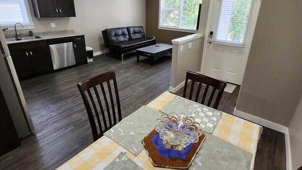 Un espacio habitable compacto con mesa, sillas, sofá y zona de cocina.