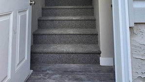 Una escalera que conduce a una puerta con alfombra texturizada.
